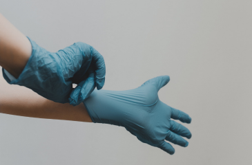 Hands putting on blue latex gloves