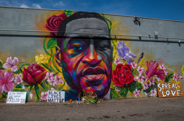 Mural of George Floyd's face surrounded by flowers and signs reading "Share Love", "Black Lives Matter", and "I'm sorry we failed you"