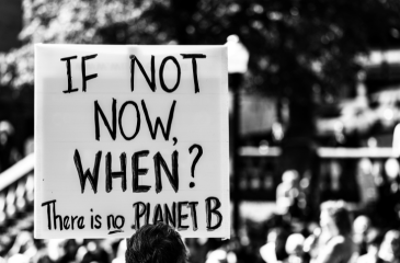 Black and white photo of a protest sign that reads "If not now, when? There is no Planet B"